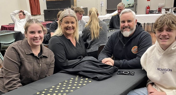 Image of one of our Year 12 students and his family seated at our Graduation Dinner and smiling for the camera.