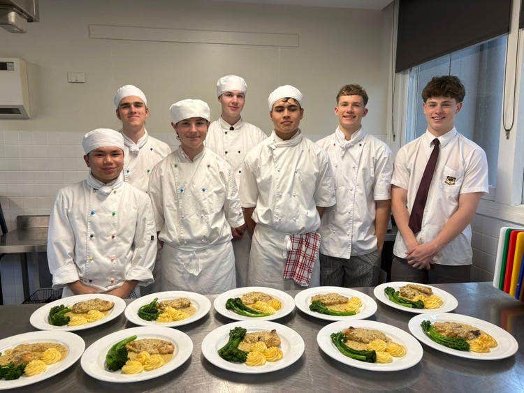 Image of seven of our Year 12 Hospitality Cookery students smiling and presenting their completed dishes.