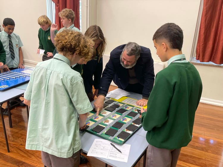Three students and their teacher participating in a mathematics incursion and putting a puzzle together.