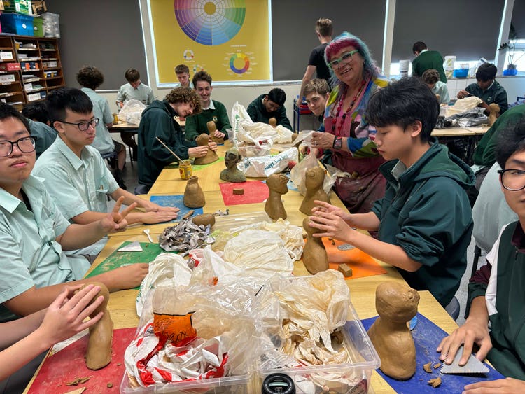 An image of eight students and their teacher at a table participating in a ceramics workshop as they work with clay to create their structures.