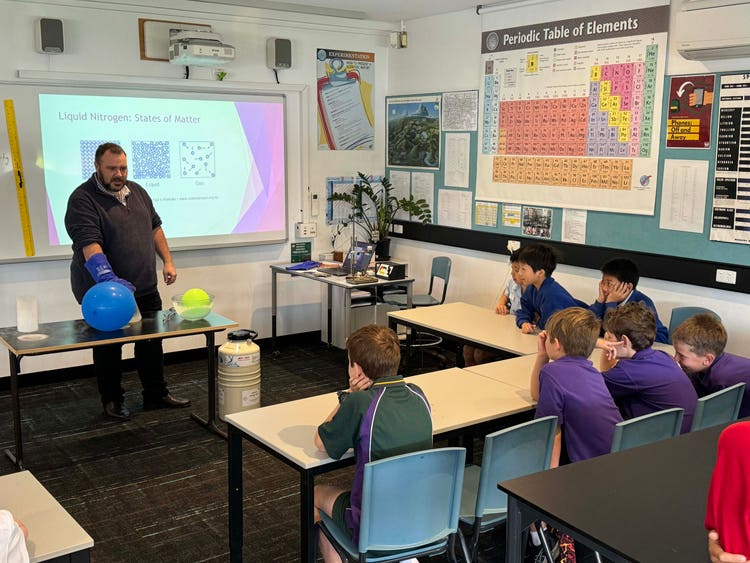 A group of students watching their teacher demonstrate the use of Liquid Nitrogen with a balloon.