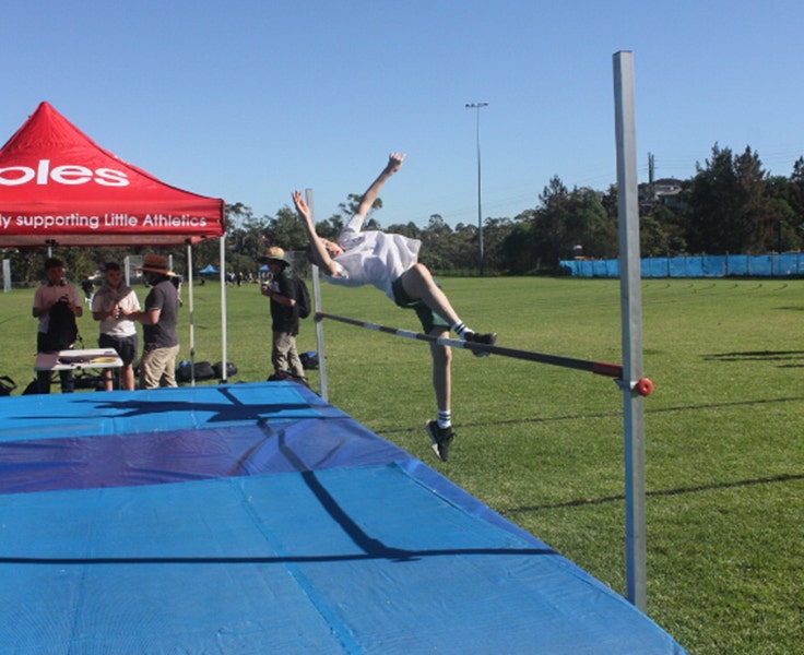 An image of one of our students in-motion as they complete a high-jump over the bar.