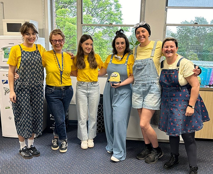 A group of teachers standing in a group together wearing matching outfits resembling the Minions characters.