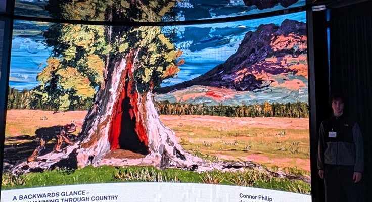 A student's HSC Major Work for Visual Arts projected on a large screen with the student artist standing next to the screen.