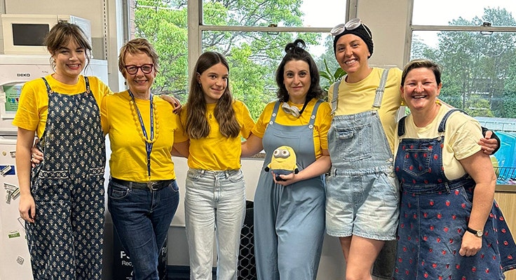 A group of teachers standing in a group together wearing matching outfits resembling the Minions characters.